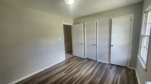 unfurnished bedroom featuring dark hardwood / wood-style floors and multiple windows