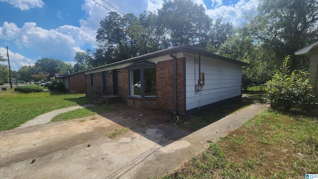 view of property exterior with brick siding and a lawn
