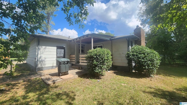 back of property with crawl space, a chimney, and a lawn