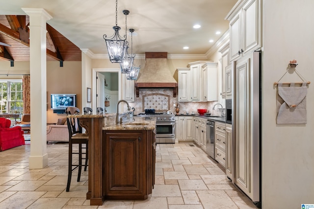 kitchen with a breakfast bar, dark stone counters, hanging light fixtures, premium appliances, and premium range hood