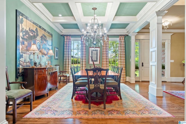 dining space with coffered ceiling, ornate columns, wood-type flooring, crown molding, and an inviting chandelier