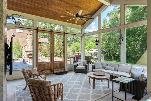 sunroom / solarium with lofted ceiling, ceiling fan, wooden ceiling, and a stone fireplace