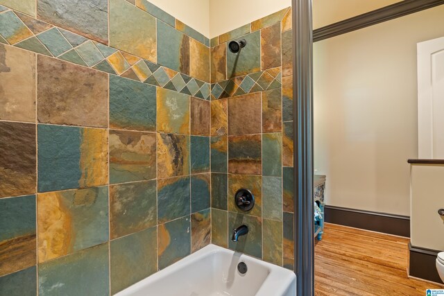 bathroom featuring tiled shower / bath combo, hardwood / wood-style flooring, and toilet