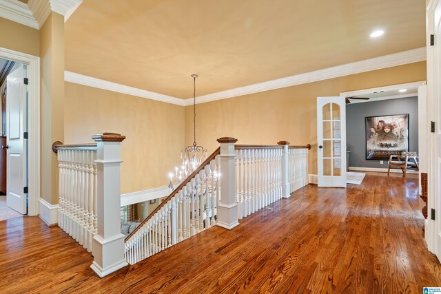 corridor with crown molding, hardwood / wood-style floors, and a chandelier