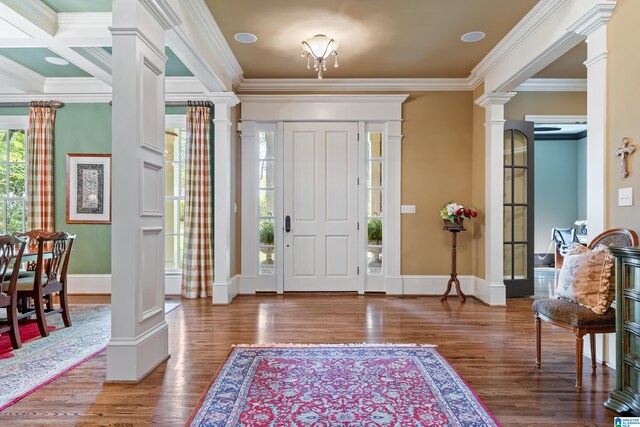 foyer entrance featuring ornamental molding, decorative columns, coffered ceiling, and dark wood-type flooring