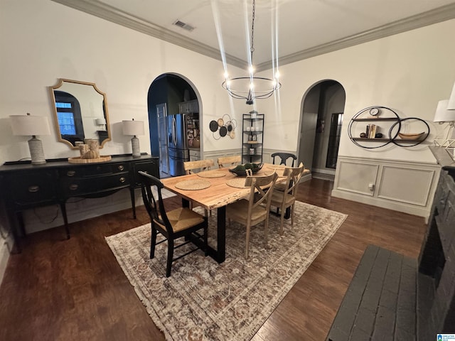 dining area featuring dark hardwood / wood-style floors, crown molding, and an inviting chandelier