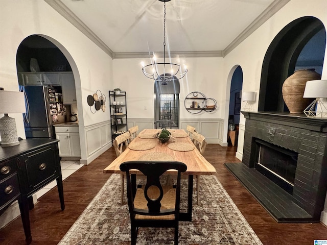 dining area with a fireplace, a chandelier, hardwood / wood-style flooring, and crown molding