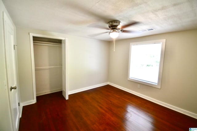 unfurnished bedroom with ceiling fan, dark wood-type flooring, and a closet