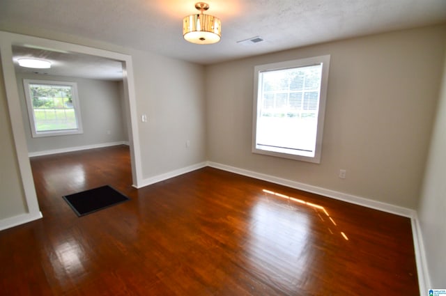 spare room with dark hardwood / wood-style floors and a textured ceiling