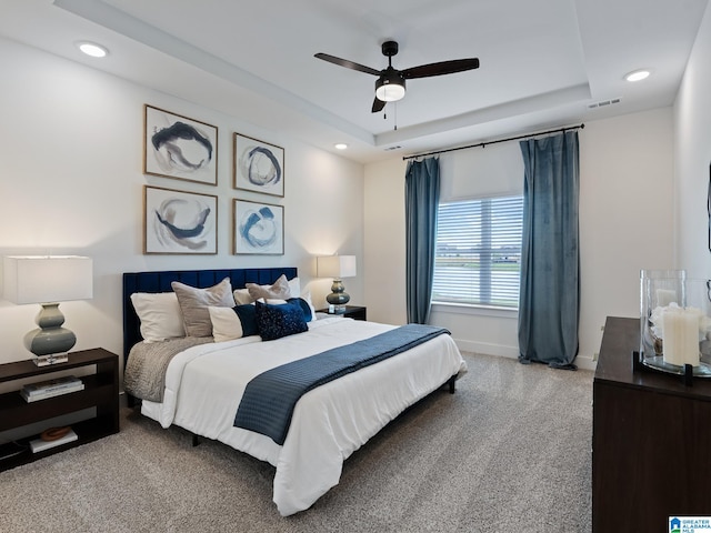 bedroom with carpet flooring, a raised ceiling, and ceiling fan