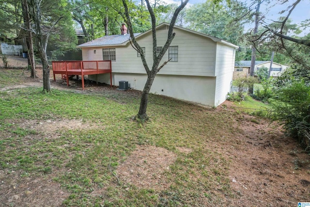 rear view of house with central AC unit, a deck, and a yard