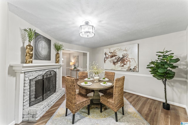 dining space with a notable chandelier, a textured ceiling, and hardwood / wood-style flooring