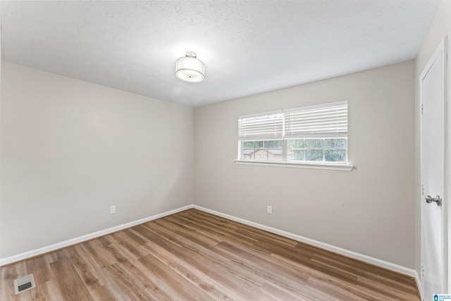 unfurnished room featuring light wood-type flooring and a textured ceiling