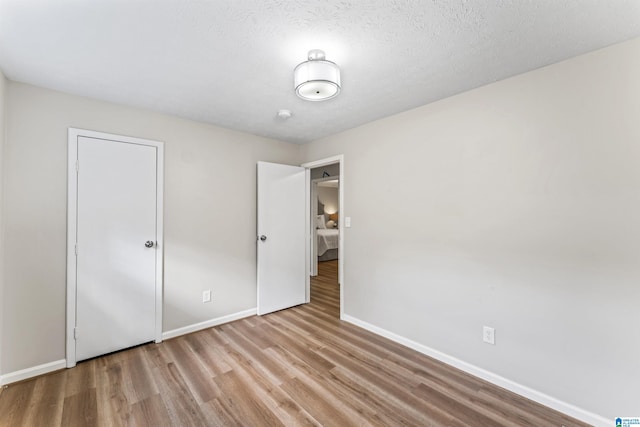 spare room featuring light hardwood / wood-style flooring and a textured ceiling