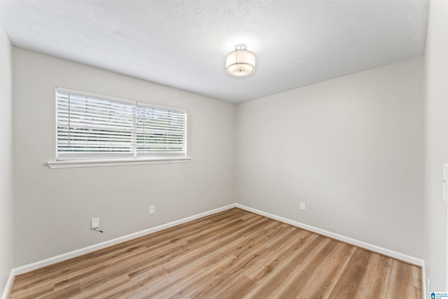 unfurnished room with a textured ceiling and light wood-type flooring