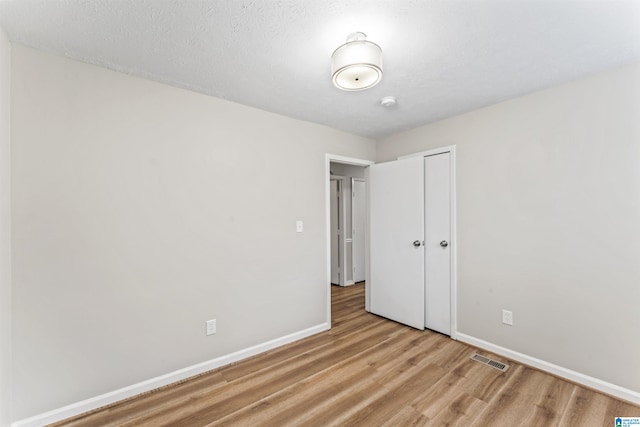 unfurnished room featuring light wood-type flooring and a textured ceiling