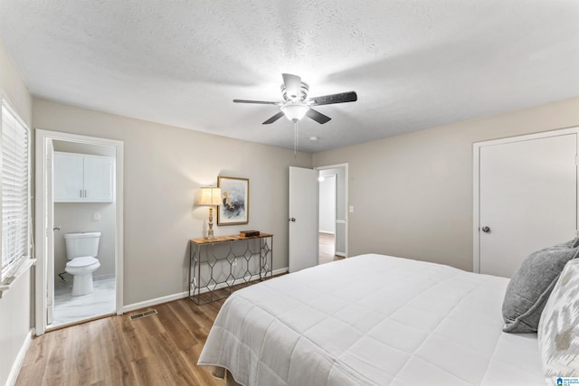 bedroom with a textured ceiling, wood-type flooring, ensuite bath, and ceiling fan