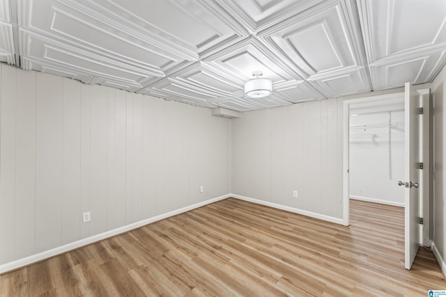 basement featuring light wood-type flooring and wood walls