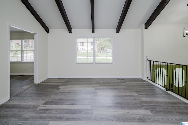 empty room with lofted ceiling with beams, plenty of natural light, and wood-type flooring