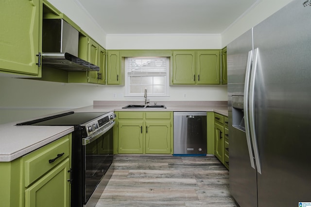 kitchen featuring stainless steel appliances, sink, wall chimney range hood, light hardwood / wood-style flooring, and green cabinets