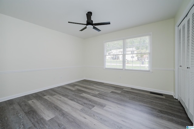 unfurnished bedroom featuring ceiling fan, a closet, and dark hardwood / wood-style flooring