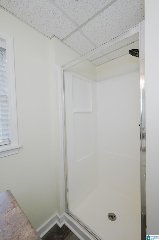 bathroom featuring a paneled ceiling, walk in shower, and wood-type flooring