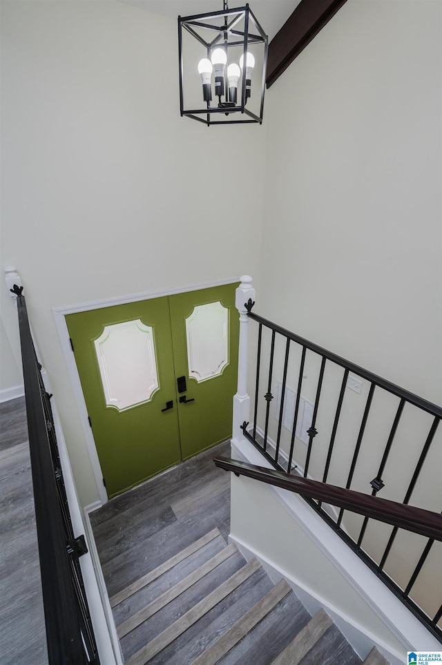 stairs featuring french doors, beamed ceiling, hardwood / wood-style flooring, and a chandelier