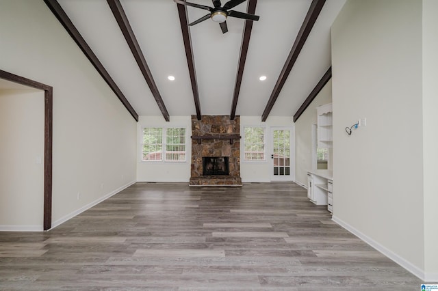 unfurnished living room with a stone fireplace, light wood-type flooring, and a healthy amount of sunlight