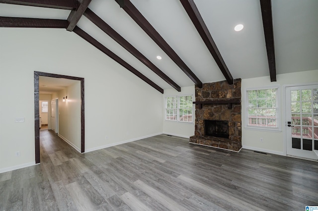 unfurnished living room with a stone fireplace, hardwood / wood-style flooring, beam ceiling, and high vaulted ceiling