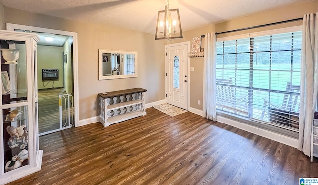 foyer entrance with a textured ceiling, an inviting chandelier, and dark hardwood / wood-style floors