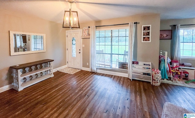 entrance foyer with a chandelier, dark wood-type flooring, and a healthy amount of sunlight