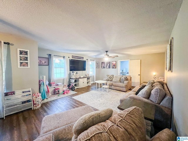 living room with a textured ceiling, ceiling fan, and dark hardwood / wood-style flooring