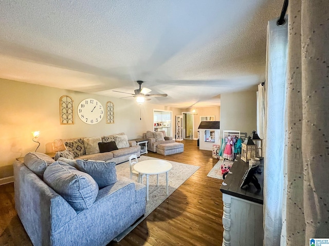 living room with ceiling fan, a textured ceiling, and dark hardwood / wood-style flooring