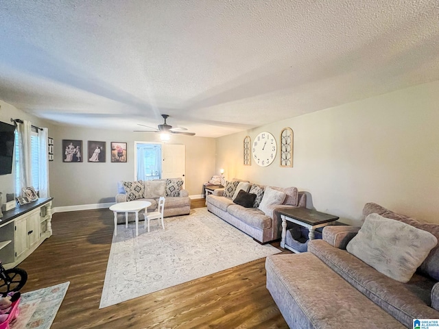 living room with a textured ceiling, ceiling fan, and dark wood-type flooring