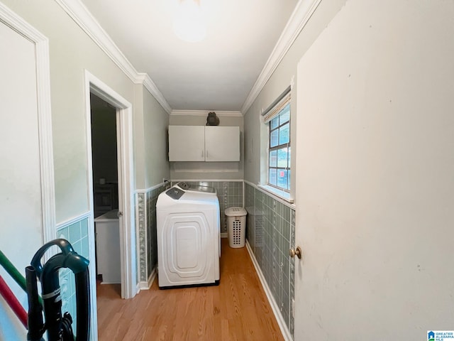 clothes washing area with cabinets, tile walls, washer / clothes dryer, light wood-type flooring, and ornamental molding