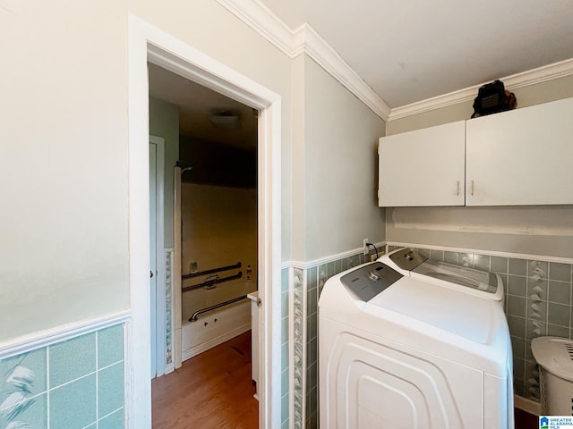 laundry area with tile walls, light hardwood / wood-style floors, cabinets, ornamental molding, and washer and dryer