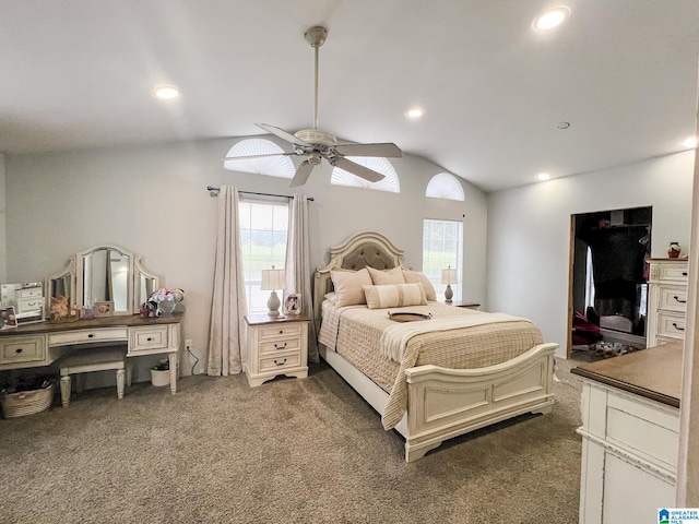 bedroom with dark colored carpet, vaulted ceiling, ceiling fan, and multiple windows