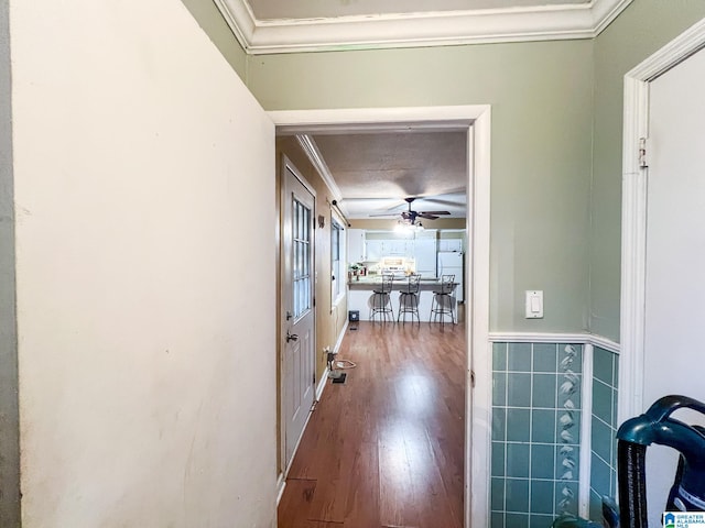 hallway with ornamental molding, wood-type flooring, and tile walls