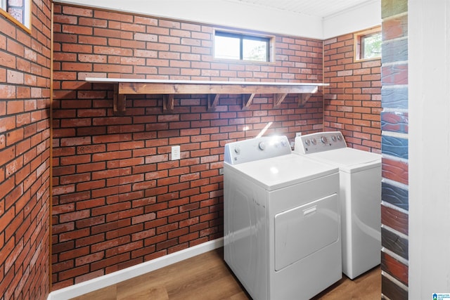 laundry area featuring brick wall, light hardwood / wood-style flooring, and plenty of natural light