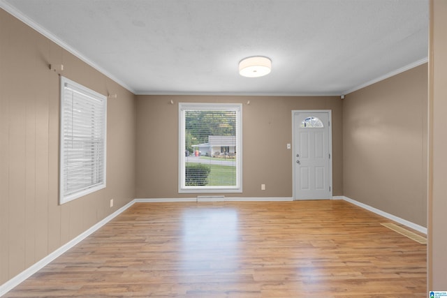 entrance foyer with a textured ceiling, crown molding, and light hardwood / wood-style floors