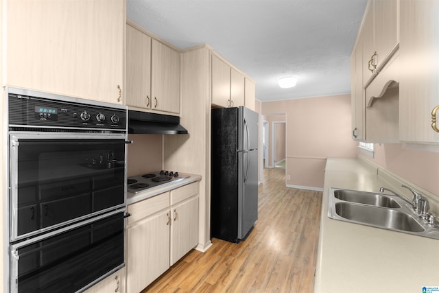 kitchen featuring light hardwood / wood-style flooring, white cooktop, sink, and stainless steel fridge