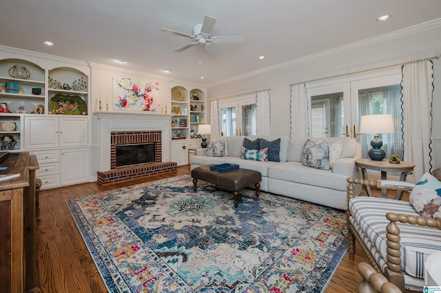 living room with a brick fireplace, a wealth of natural light, dark wood-type flooring, and ceiling fan