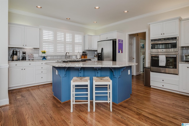 kitchen featuring a kitchen bar, a center island, stainless steel appliances, and white cabinets