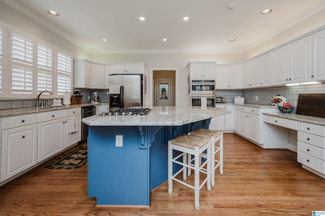 kitchen with light hardwood / wood-style flooring, stainless steel appliances, white cabinets, and a center island