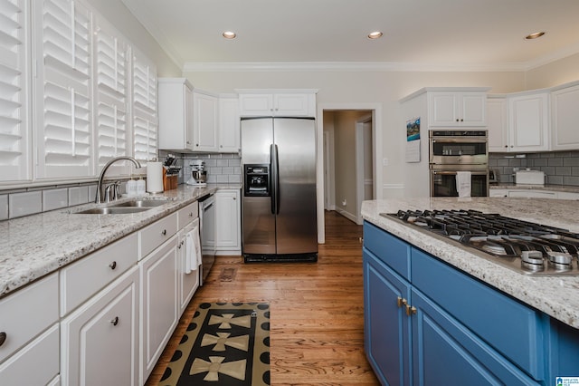 kitchen with stainless steel appliances, hardwood / wood-style flooring, blue cabinetry, and tasteful backsplash