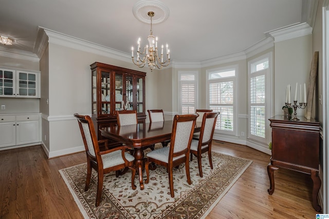 dining space with light hardwood / wood-style flooring, a chandelier, and crown molding