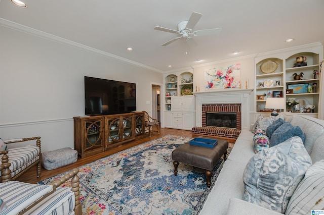 living room with wood-type flooring, built in shelves, a fireplace, and ceiling fan