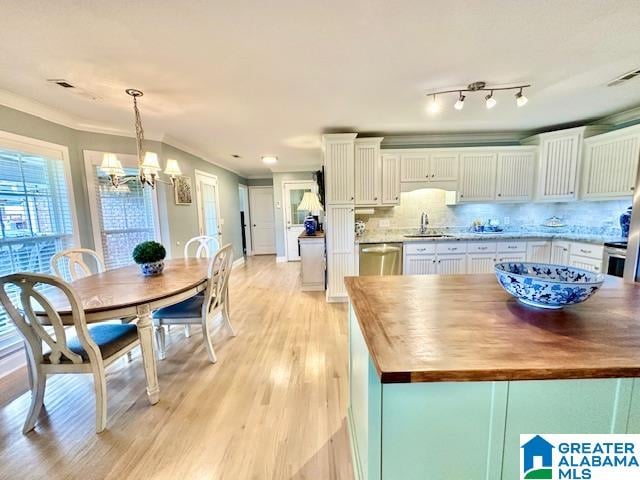 kitchen with light hardwood / wood-style flooring, sink, pendant lighting, and white cabinets