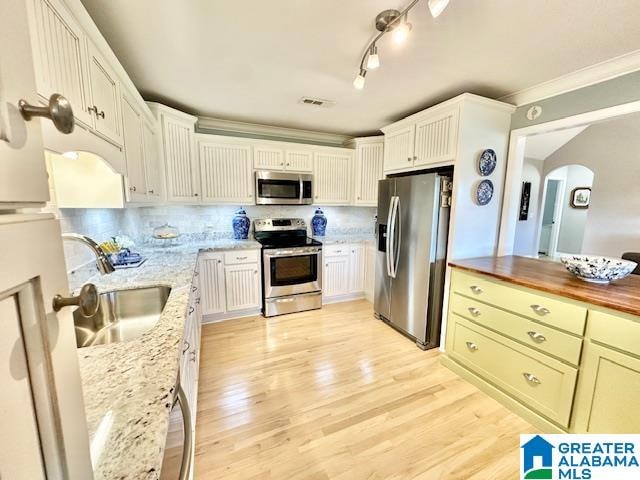 kitchen featuring appliances with stainless steel finishes, backsplash, butcher block countertops, light hardwood / wood-style flooring, and sink