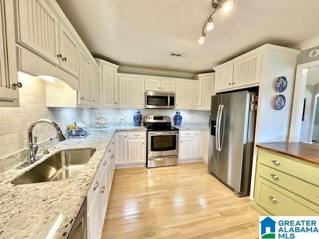 kitchen with light wood-type flooring, sink, white cabinets, appliances with stainless steel finishes, and butcher block countertops